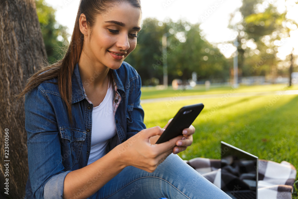 Beautiful young woman student in the park using mobile phone. Beautiful young woman student in the park using mobile phone.