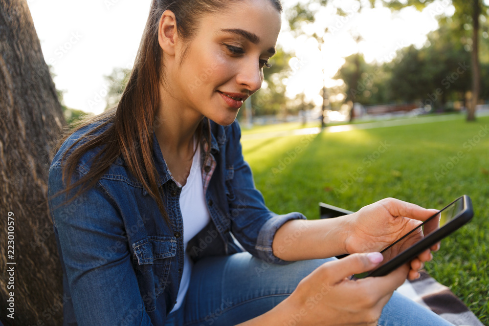 Beautiful young woman student in the park using mobile phone. Beautiful young woman student in the park using mobile phone.