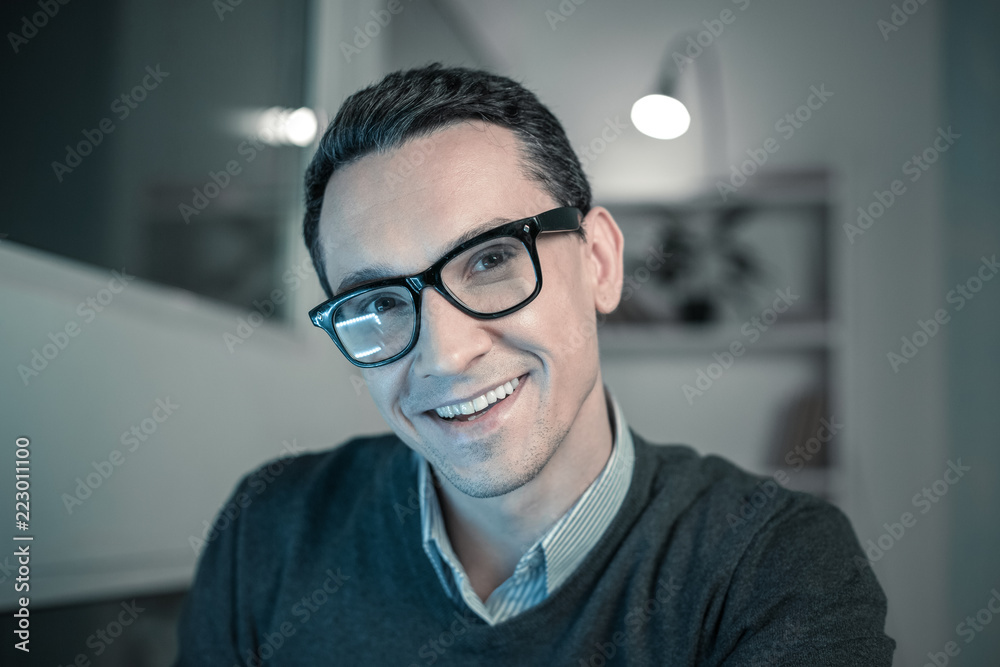 Creative idea. Portrait of young smiling man in glasses sitting at the office thinking about something Creative idea. Portrait of young smiling man in glasses sitting at the office thinking about something