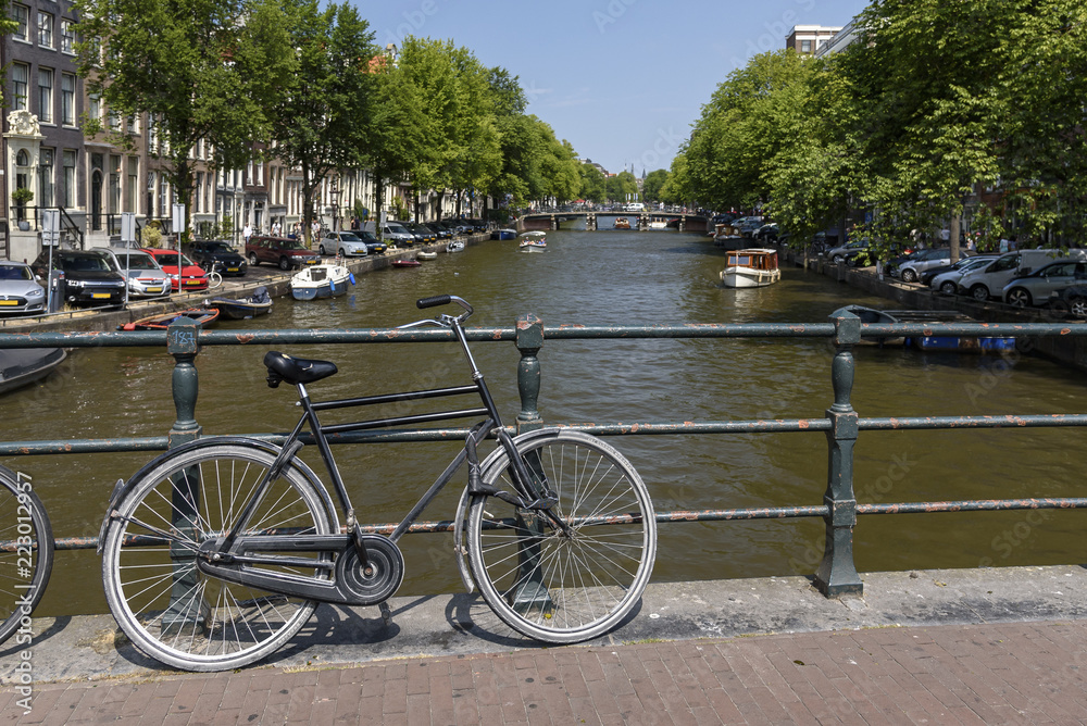 A single bicycle leaning against a railing, overlooking a canal in Amsterdam, on a summers day