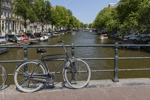 A single bicycle leaning against a railing, overlooking a canal in Amsterdam, on a summers day