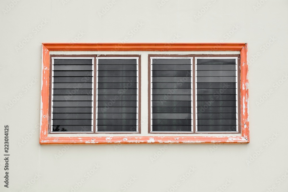 orange antique glass window on white cement wall