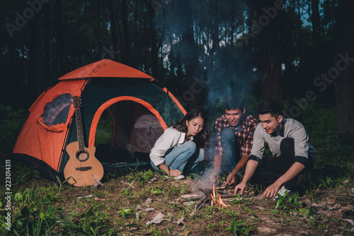 Group of friends are happy enjoying drunk and talking near a tent stay the night, they enjoy relaxing camp in the jungle vacation holidays concept.