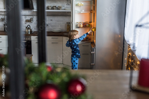 selective focus of little boy on pajamas opening refrigerator