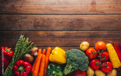 Top view of a wooden table with several types of vegetables in the lower part of the image