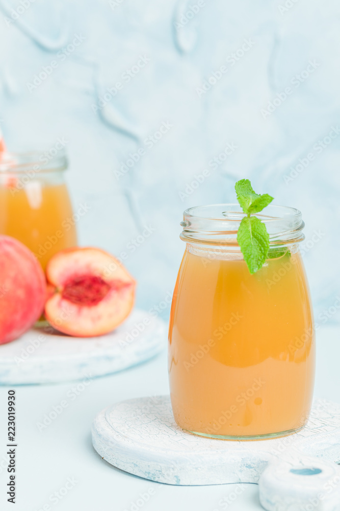 Peach smoothie in glass jars with fresh ripe fruits and green mint leaves on blue pastel background. Peach smoothie in glass jars with fresh ripe fruits and green mint leaves on blue pastel background.