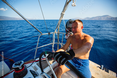 Man at the helm sail boat, the ship controls during sea yacht race. © De Visu