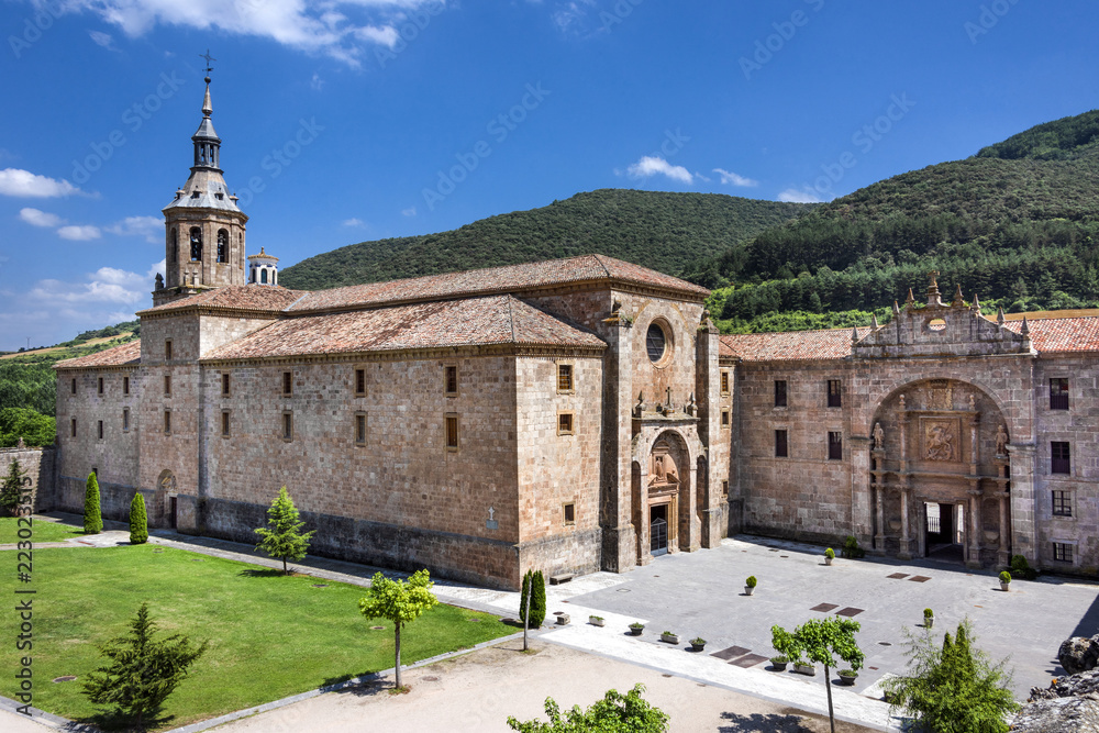 Spain, La Rioja, San Millan de la Cogolla: Panoramic view of famous Monastery of San Millan de Yuso with public park, hills and blue sky. It's the birthplace of modern written spoken Spanish language.