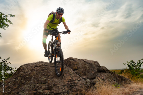 Fototapeta Naklejka Na Ścianę i Meble -  Cyclist Riding the Bike on Autumn Rocky Trail at Sunset. Extreme Sport and Enduro Biking Concept.