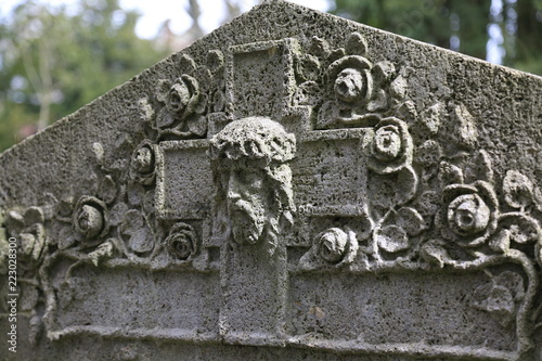 Grabstein mit Kreuz und Jesuskopf auf einem Friedhof in Frankfurt. photo