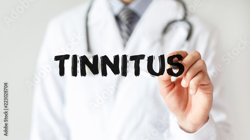 Doctor writing word TINNITUS with marker, Medical concept photo