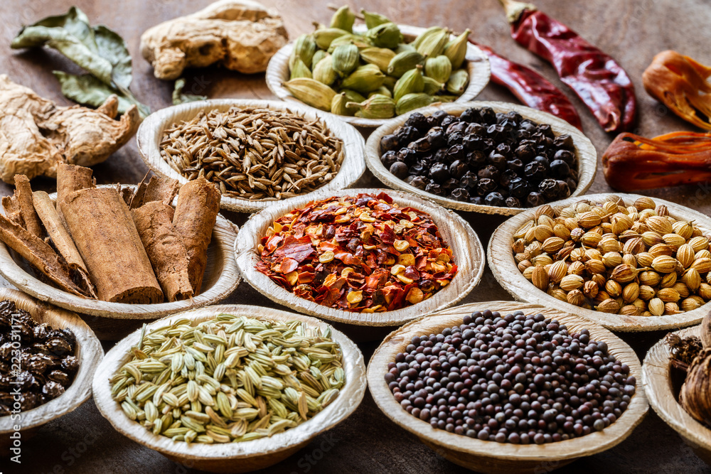 Group of Indian spices in coconut bowls on wooden background close-up