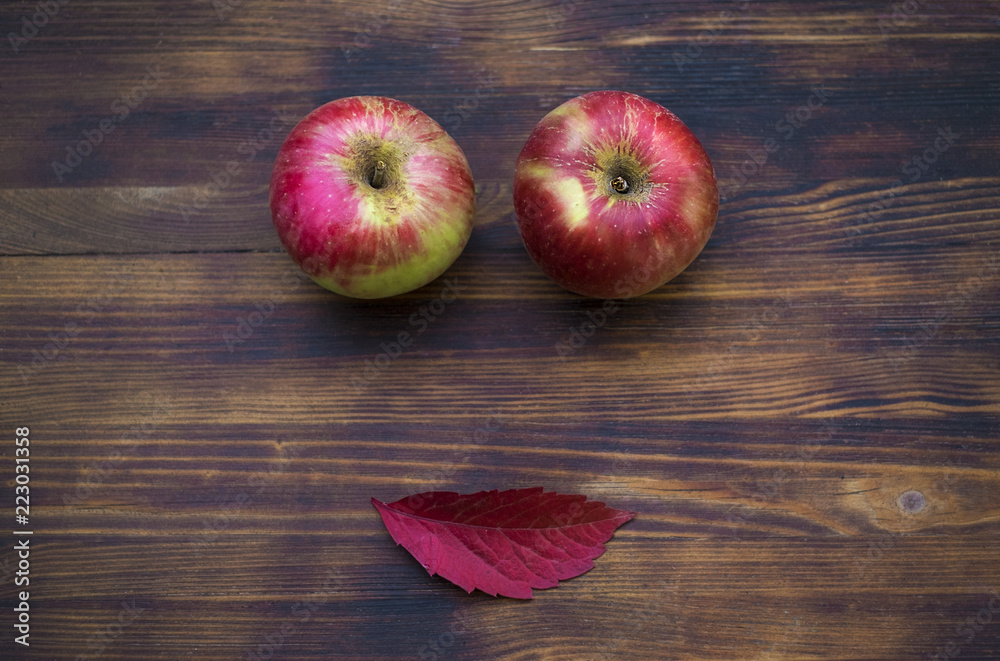 Two red apples and autumn leaf on the wooden background Two red apples and autumn leaf on the wooden background