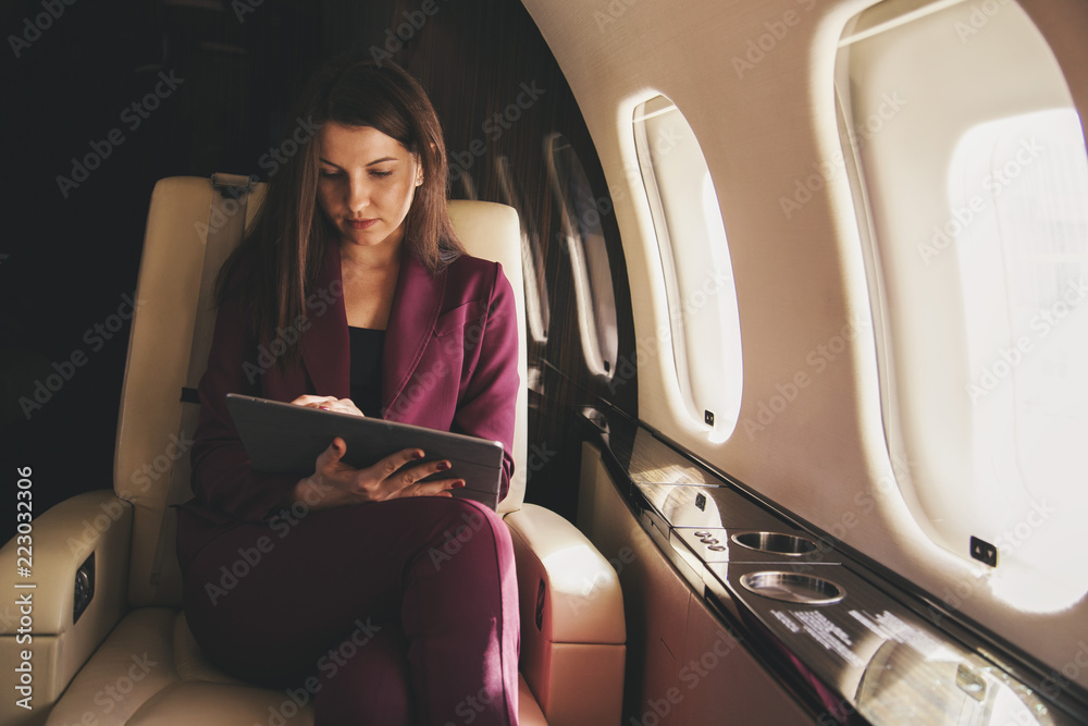 Naklejka premium piękna młoda kobieta siedzi w samolocie i pracuje na laptopie