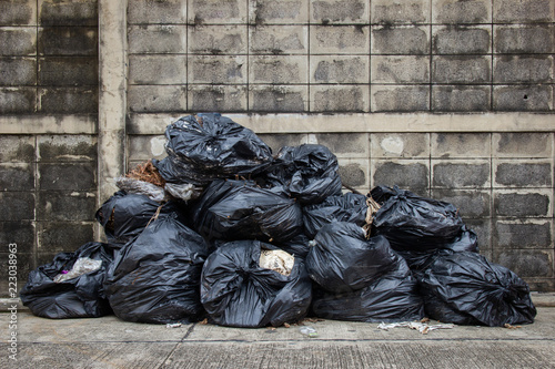 Bag trash on street or sidewalk with old brick wall for background.