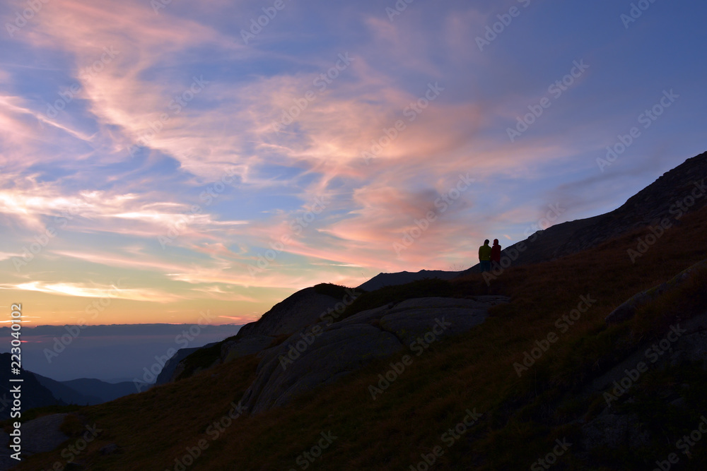Young couple admiring sunset in mountain. Ivan Vazov Hut, Rila Mountains, Bulgaria Young couple admiring sunset in mountain. Ivan Vazov Hut, Rila Mountains, Bulgaria