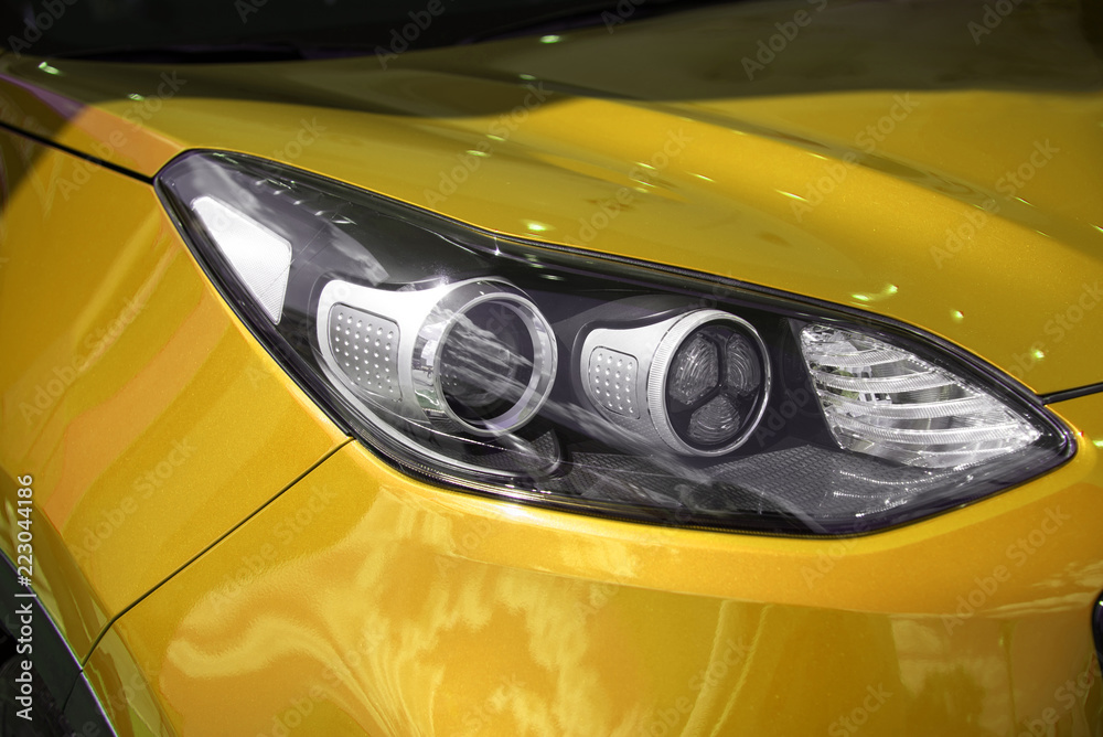 clean white headlight of a new yellow luxury car from the saloon. close-up of the front left headlight
