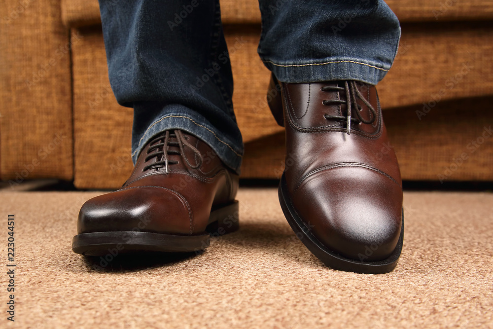 Men's legs in jeans shod in classic brown Oxford shoes Men's legs in jeans shod in classic brown Oxford shoes
