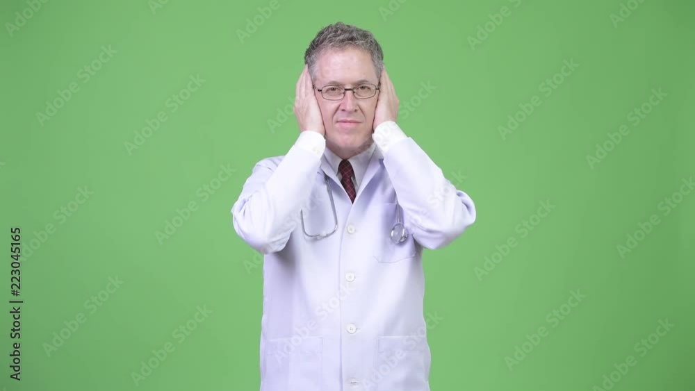 Portrait of mature man doctor covering ears as three wise monkeys concept Portrait of mature man doctor covering ears as three wise monkeys concept