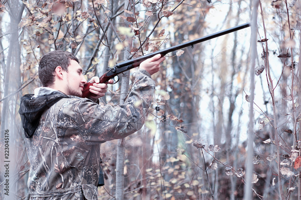 Naklejka premium A man in camouflage and with a hunting rifle in a forest on a sp