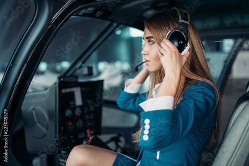 Female pilot in headphones in helicopter cabin