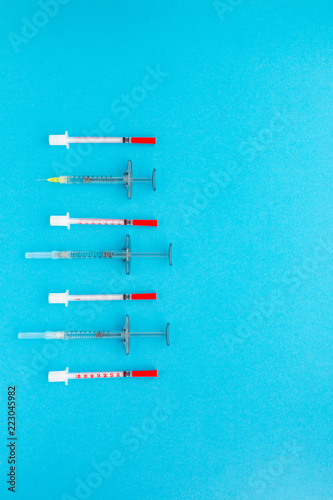Syringes organized in a row over blue background, top view. Mock up health care medical background.