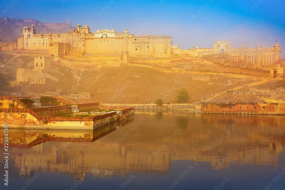 Amber Fort in Jaipur, Rajasthan, India in the early morning with mist, on sunrise, with reflection on a lake.