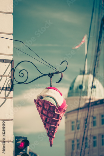 Big plastic ice cream cone sign over blue sky on city street