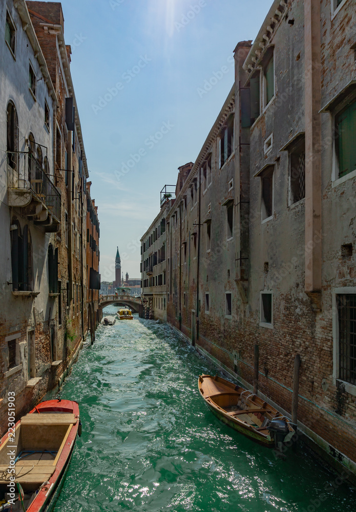 Narrow canal with green wather in Venice, Veneto, Italy