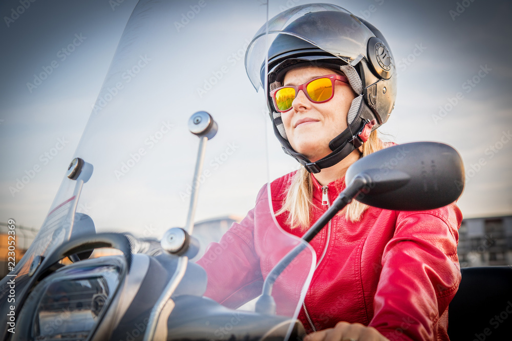 Young woman riding scooter in the city. Portrait of a beautiful woman with a moped Young woman riding scooter in the city. Portrait of a beautiful woman with a moped