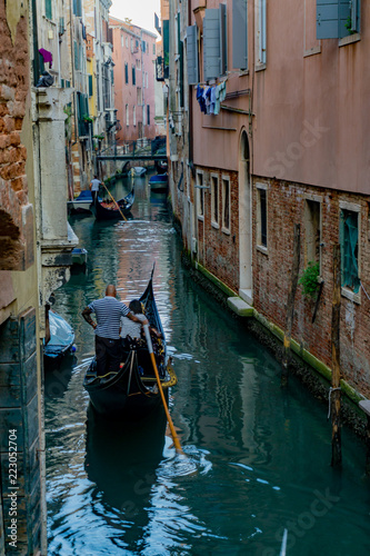 Venetian gondolier punting gondola through narrow canal waters of Venice, Veneto, Italy © marcodotto