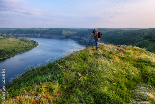 photographer on the cliff above the river. the tourist watches the sunset over the canyon