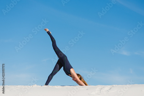 Body tilt down yoga exercise in desert outdoors