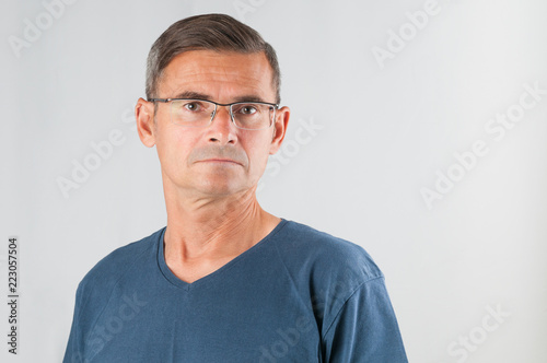 Portrait senior serious man in eyeglasses on gray background © unclepodger