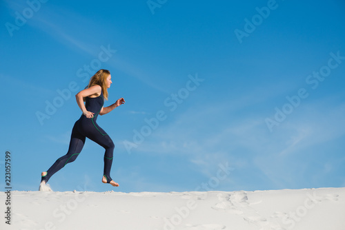 Active woman in sport wear jogging in desert