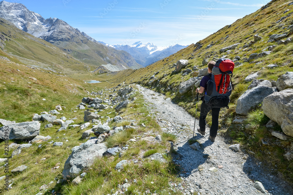 A hiker walking on a path in the mountain near the Matterhorn