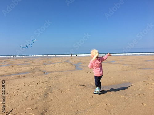 Girl flying kite at Watergate Bay beach Cornwall