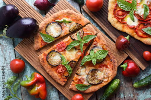 Healthy vegetarian food. Homemade Italian pizzas with aubergines, tomatoes and basil on oak cutting boards with raw ingredients