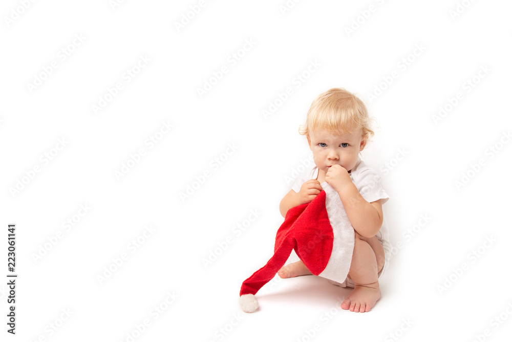 baby girl sitting on his haunches with a Santa Claus hat isolated on white background. child and christmas cap baby girl sitting on his haunches with a Santa Claus hat isolated on white background. child and christmas cap