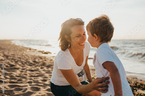 Pregnant Mother And Her Little Boy At The Beach At Sunset