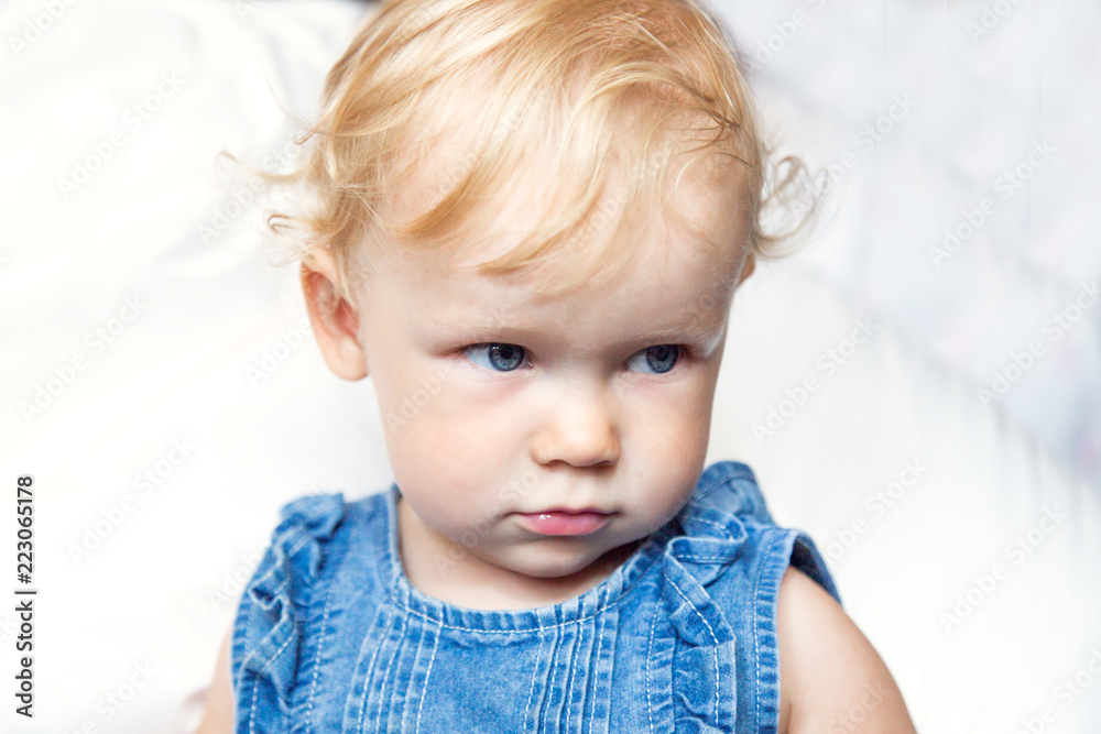 Naklejka premium portret curly-haired blue-eyed little baby girl in jeans clothes