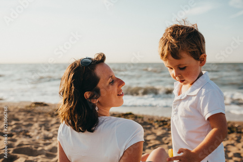 Pregnant Mother And Her Little Boy At The Beach At Sunset