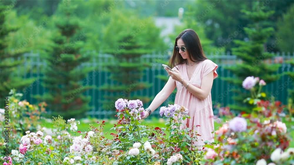 Young girl in a flower garden among beautiful roses. Smell of roses Young girl in a flower garden among beautiful roses. Smell of roses