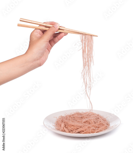 Hand holding wheat thin noodles by chopsticks on a dishl isolated on white background photo