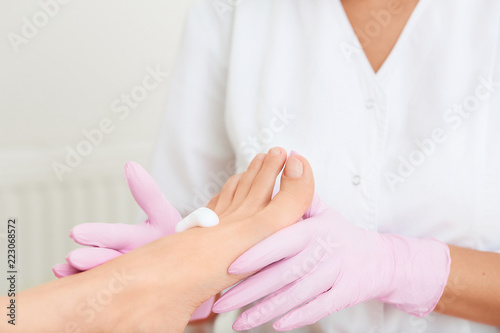 Professional foot massage using moisturizing foam.Final stage of professional pedicure.Skin softener  smoothing out hard skin.Patient visiting podiatrist. Foot treatment in SPA salon.Podiatry clinic.