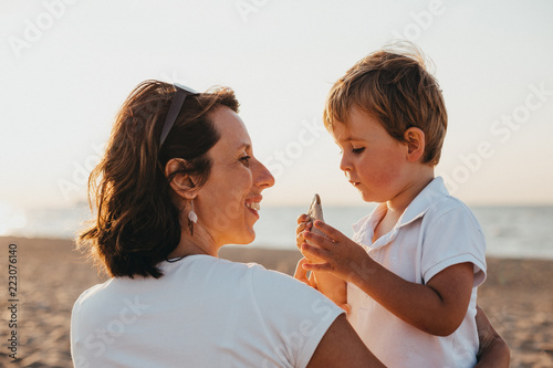 Pregnant Mother And Her Little Boy At The Beach At Sunset
