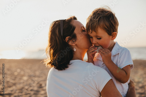 Pregnant Mother And Her Little Boy At The Beach At Sunset