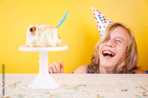 Teenage girl enjoying herself after ruining birthday cake. One person party. Concept of birthday party, messthetics and misconduct photo