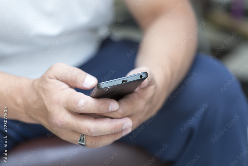 A man is sitting and reading an SMS on his mobile phone A man is sitting and reading an SMS on his mobile phone