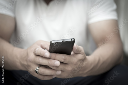 A man is sitting and reading an SMS on his mobile phone